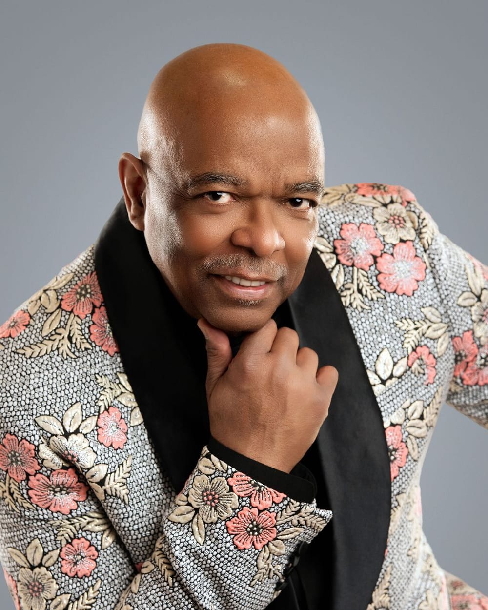 Sheldon Price in a floral jacket, hand at his chin